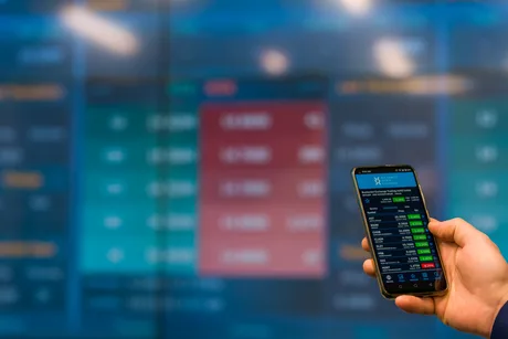 Un telefon mobil afișează date financiare pe un ecran digital.