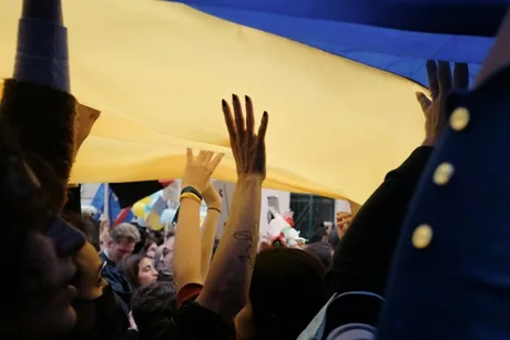 Oameni susținând steagul Ucrainei în timpul unui protest.