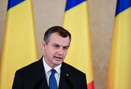 Eugen Tomac discutând despre programul de guvernare în fața drapelului României.