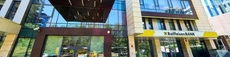 Sediul Raiffeisen Bank cu fațadă modernă și logo vizibil.