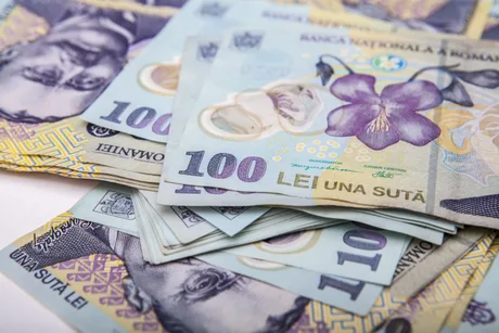 Bancnote de 100 lei aranjate pe o suprafață plană.