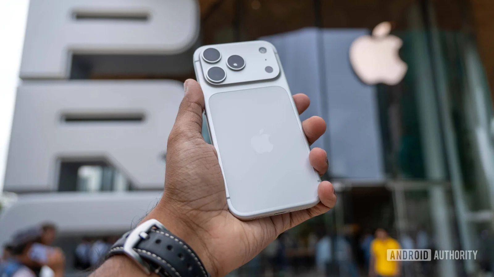 Un smartphone Apple este ținut în mână, cu logo-ul Apple vizibil în fundal.