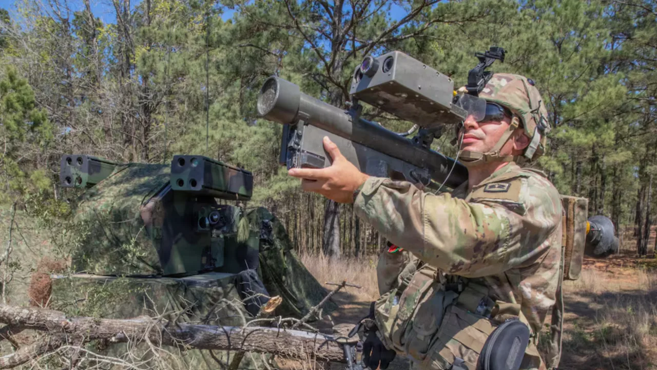 Soldat pregătit să lanseze o rachetă antidrone în teren forestier.