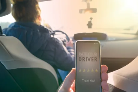 Un șofer de ridesharing cu telefonul în mână, evaluând serviciul.