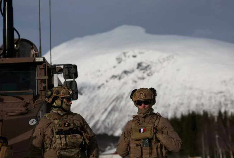 Soldați în echipament militar, pe fundalul unui peisaj montan acoperit de zăpadă.