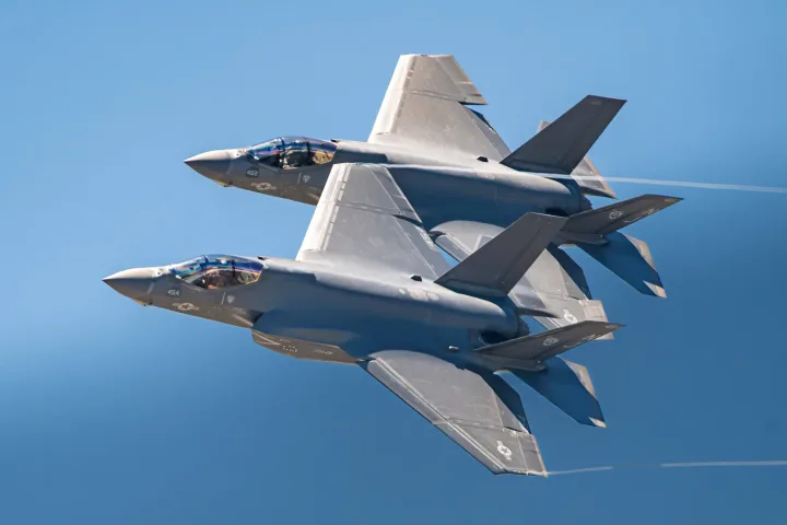 Două avioane F-35 zburând în tandem pe cerul albastru.