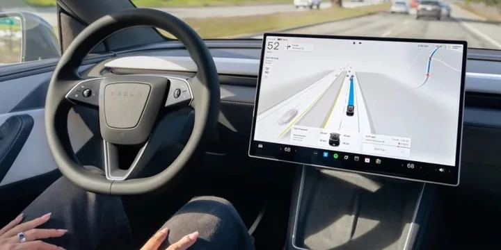 Interiorul unei mașini Tesla cu ecran de control și volan.