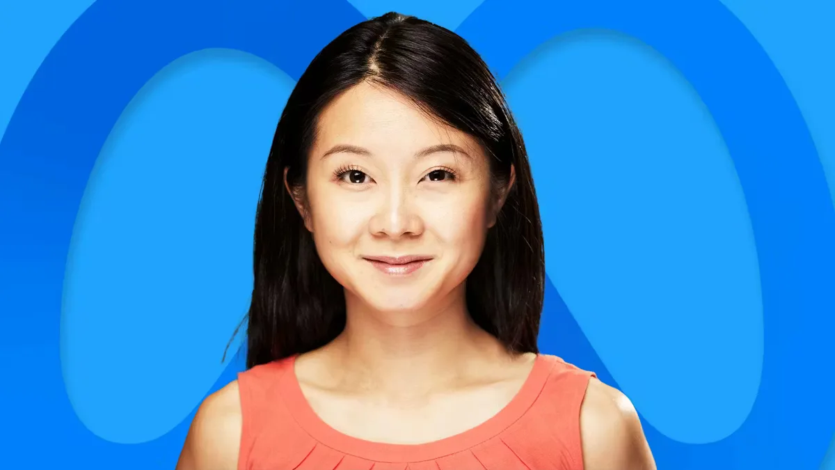 Susan Li, directoarea financiară a Meta, zâmbind în fața logo-ului companiei.