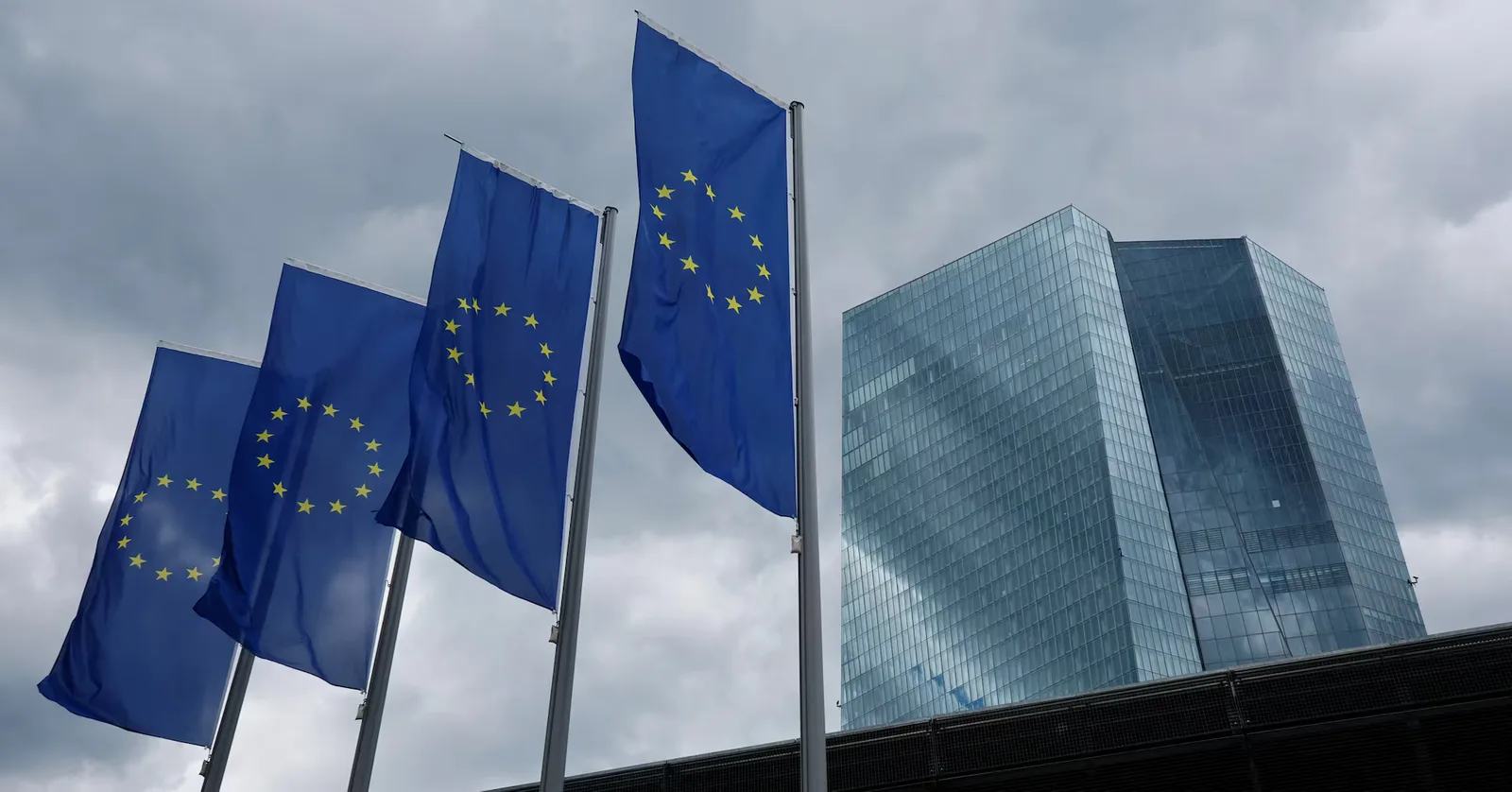 Clădire modernă cu steaguri europene fluturând în vânt.