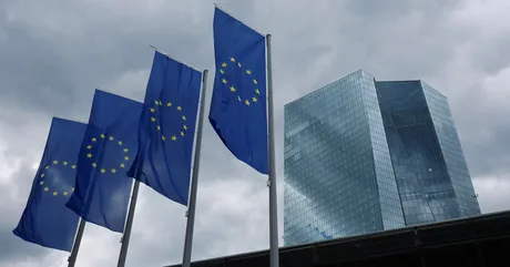 Clădire modernă cu steaguri europene fluturând în vânt.