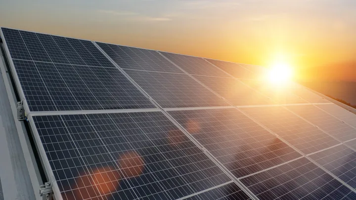 Panouri solare pe acoperișuri captând lumina soarelui la apus.