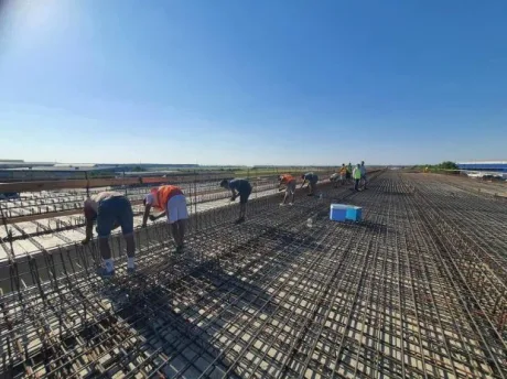Muncitori pe șantierul Autostrăzii Bucureștiului, lucrând intens pentru finalizare.