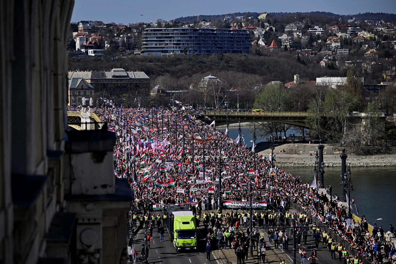 Mii de oameni participă la marșuri politice în Budapesta, cu steaguri și pancarte.