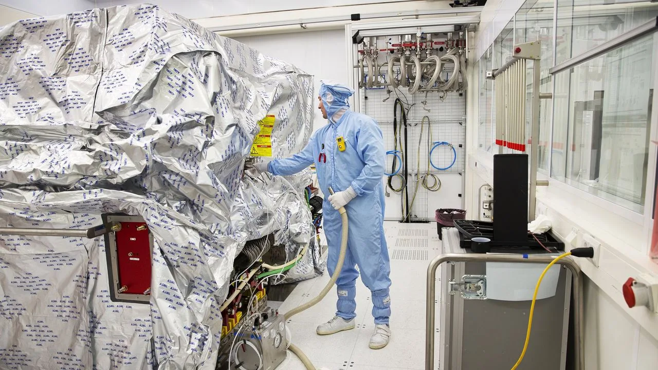 Un tehnician în echipament de protecție lucrează într-o fabrică de semiconductori.