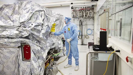 Un tehnician în echipament de protecție lucrează într-o fabrică de semiconductori.