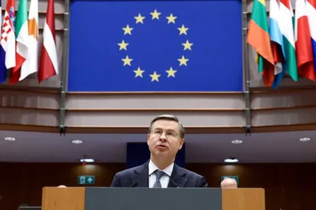 Valdis Dombrovskis vorbește la summitul european, steaguri în fundal.