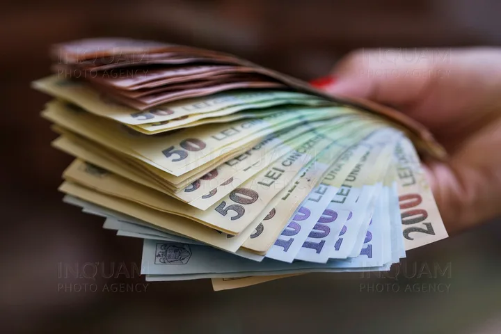 Bancnote românești de diverse valori, aranjate într-o mână.