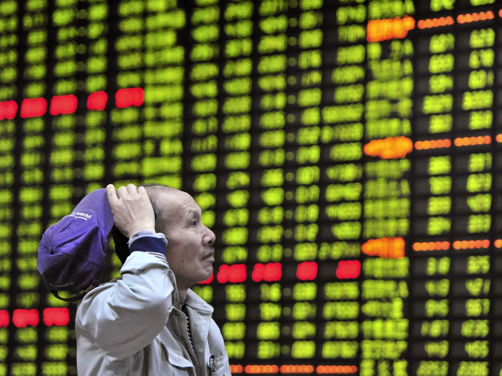 Investitor analizând datele bursiere pe un panou electronic.
