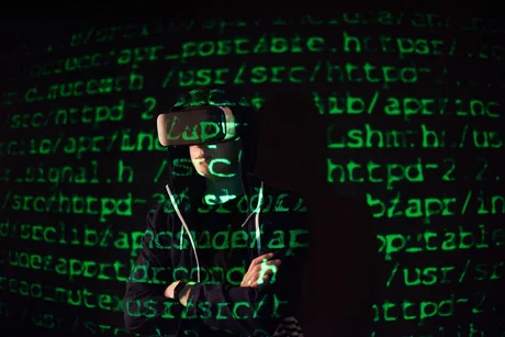 Persoană cu ochelari VR în fața unui fundal de cod cibernetic.
