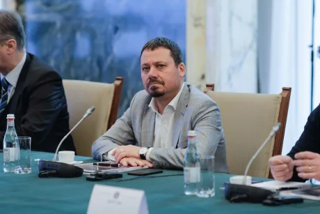 Un bărbat în costum, la o întâlnire oficială, cu un aer contemplativ.