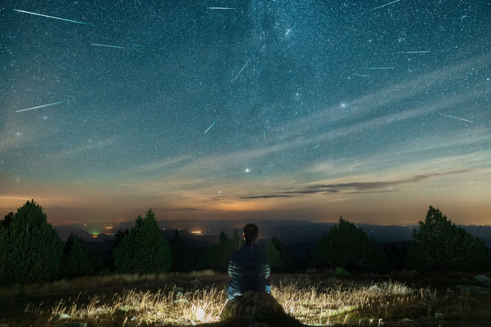 Cerul plin de meteori în noaptea Perseidelor, observat dintr-o zonă întunecată.