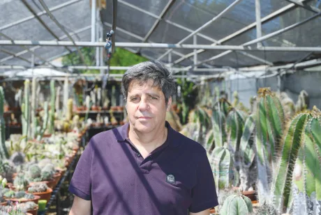 Cercetător în seră, înconjurat de plante biofortificate.