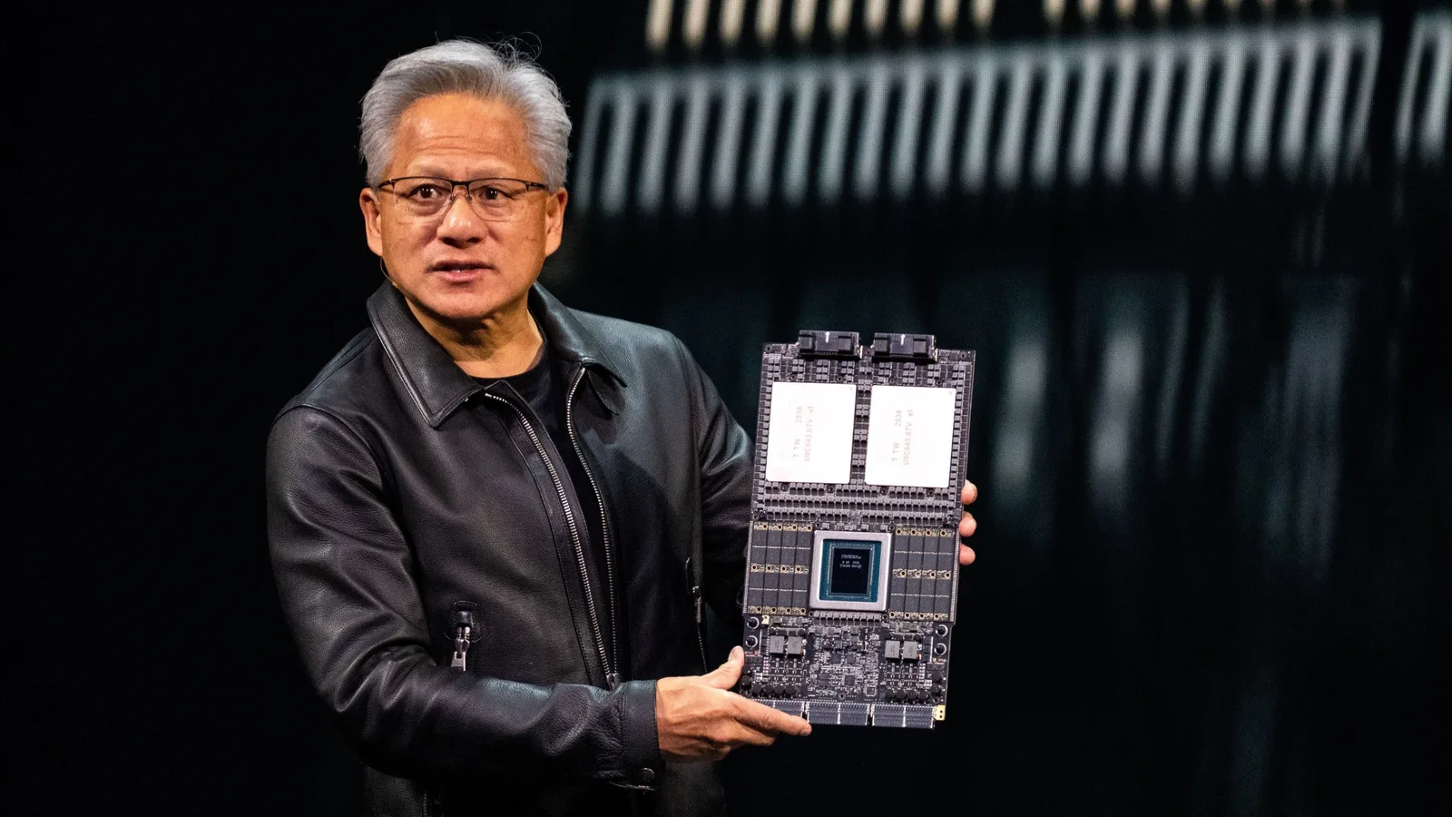 Jensen Huang prezintă un procesor Nvidia pe scenă, evidențiind inovațiile tehnologice.