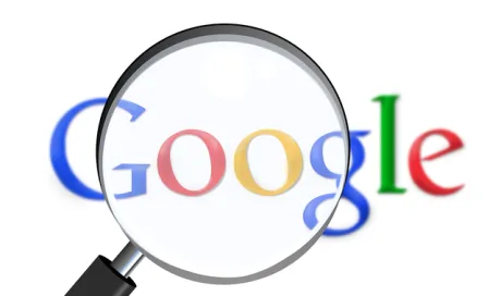 Logo-ul Google sub o lupă, simbolizând căutarea informațiilor.
