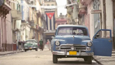 O stradă din Havana cu mașini clasice și steagul Cubei.