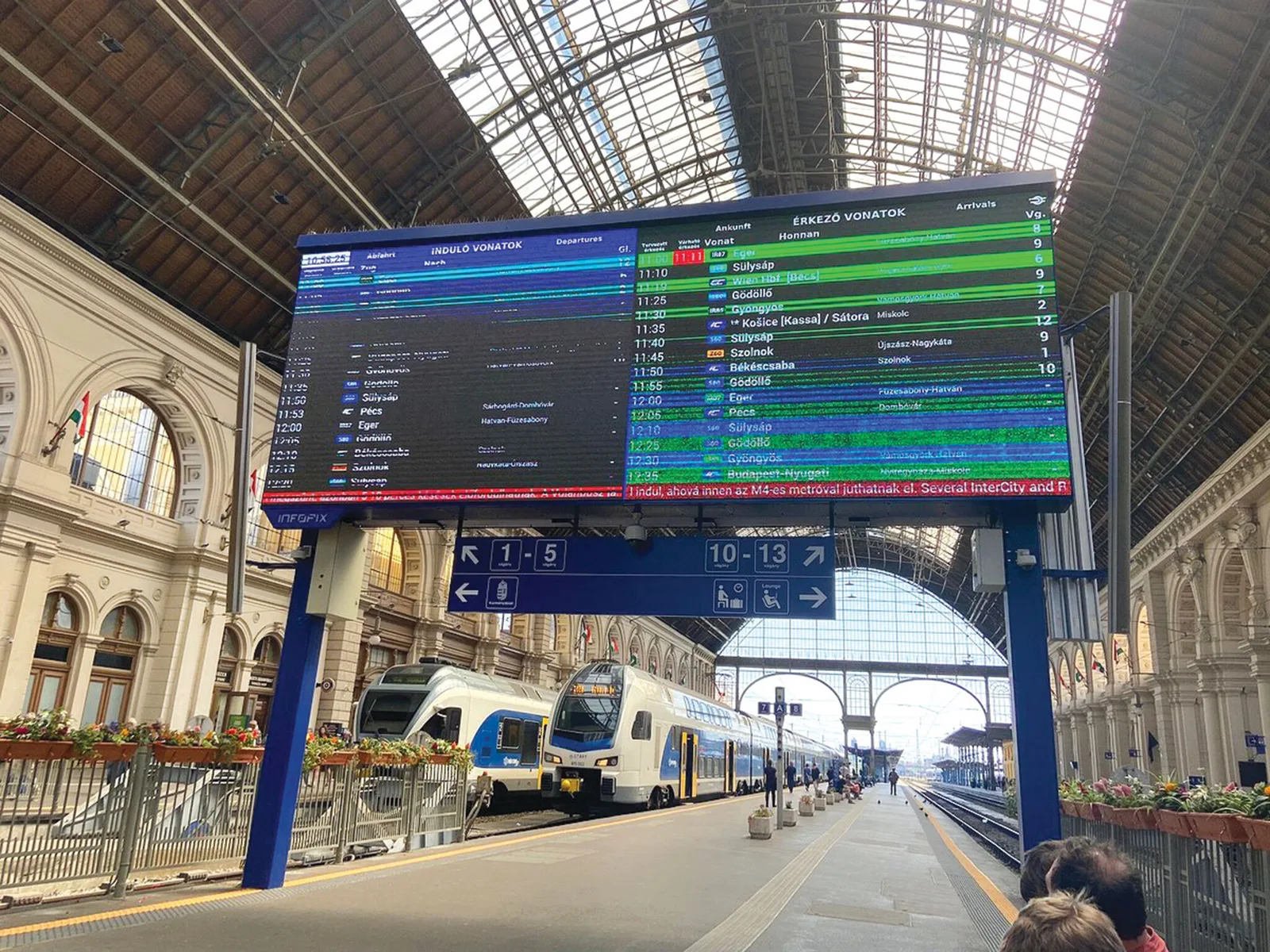 Infrastructură feroviară modernizată în Ungaria, cu trenuri și informații despre plecări.