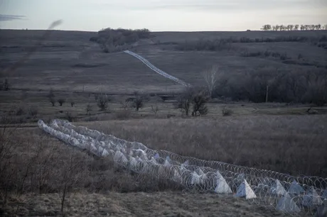 Peisaj rural din Donbas, cu sârma ghimpată și câmpuri întinse.