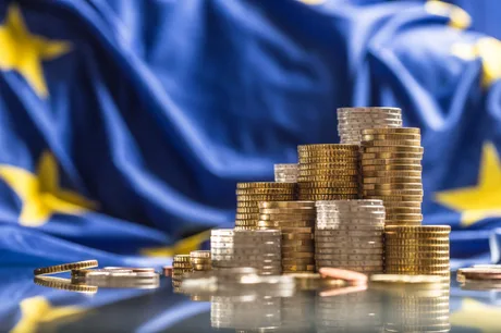 Monede aranjate pe un fundal cu steagul Uniunii Europene.