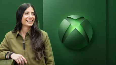 Asha Sharma zâmbește în fața logo-ului Xbox, simbolizând schimbări în companie.