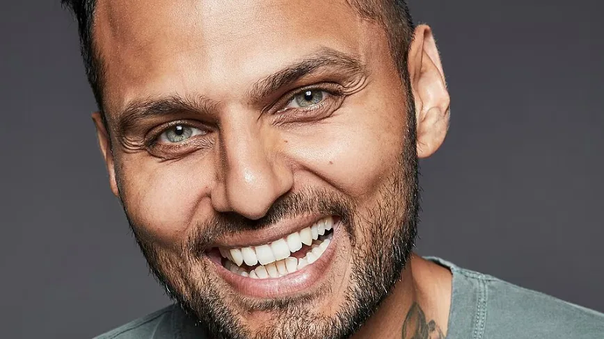 Jay Shetty zâmbind, cu un fundal neutru, promovând podcastul său.