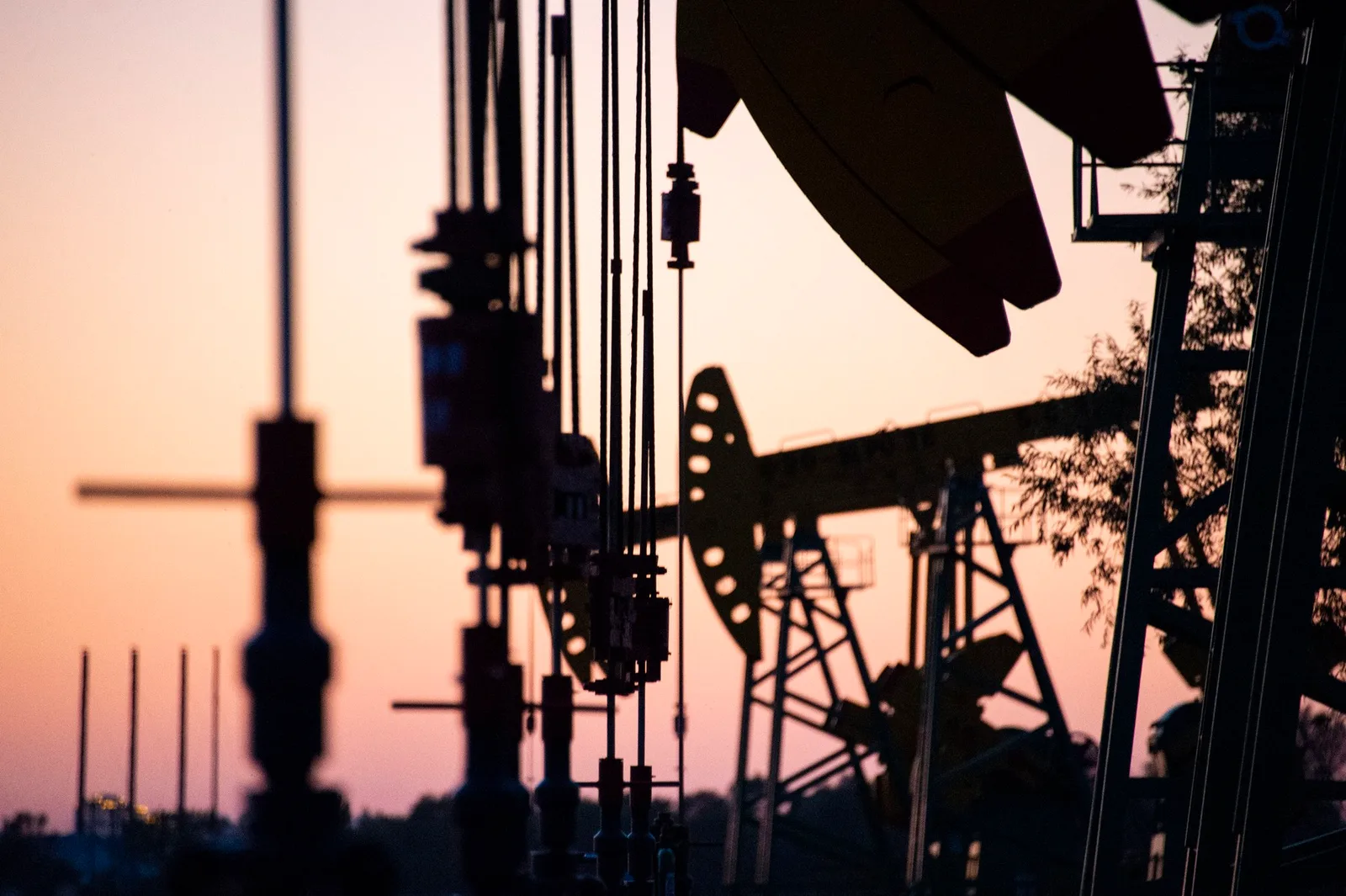 Silhouete de echipamente petroliere la apus, simbolizând influența Chinei în piața petrolului.