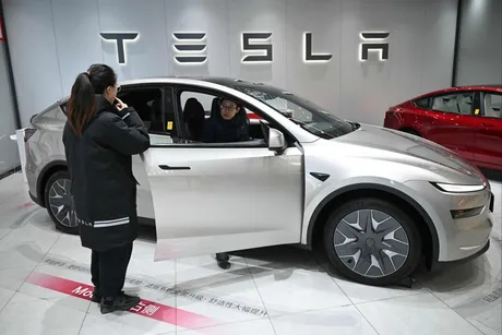 Un client examinează un Model Y Tesla într-un showroom modern.