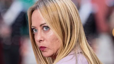 Giorgia Meloni, premierul Italiei, cu o expresie serioasă, înconjurată de oameni.