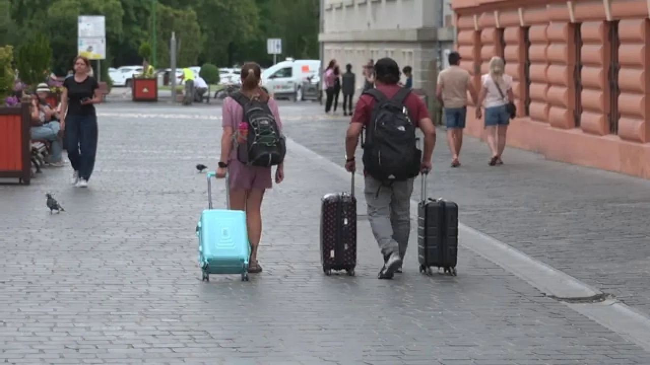Angajați români plecând în concediu, cu bagaje, pe o stradă aglomerată.