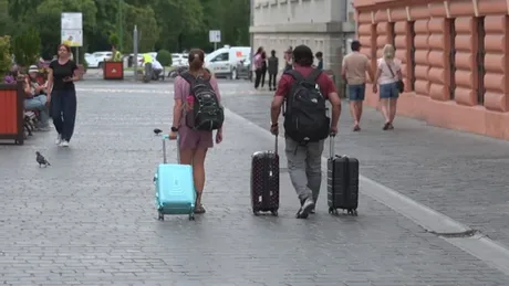 Angajați români plecând în concediu, cu bagaje, pe o stradă aglomerată.