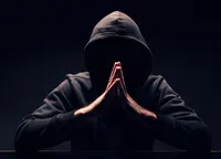Siluetă misterioasă a unei persoane cu mâinile împreunate, în întuneric.