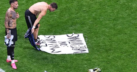 Jucători argentinieni cu banner controversat pe terenul de fotbal.