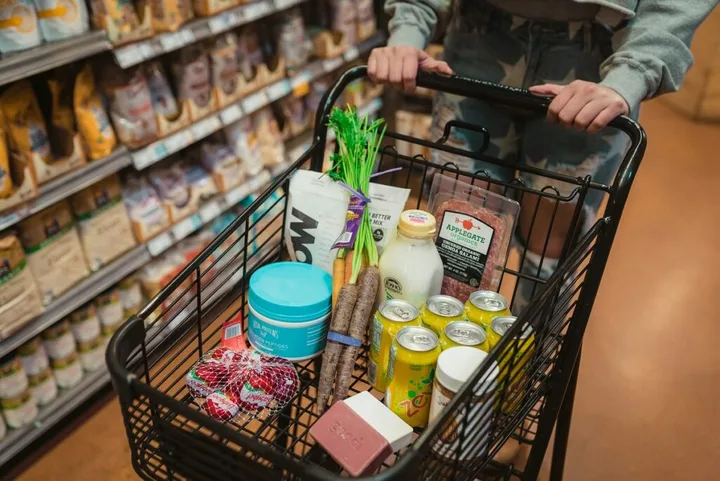 Coș de cumpărături plin cu alimente variate în supermarket.