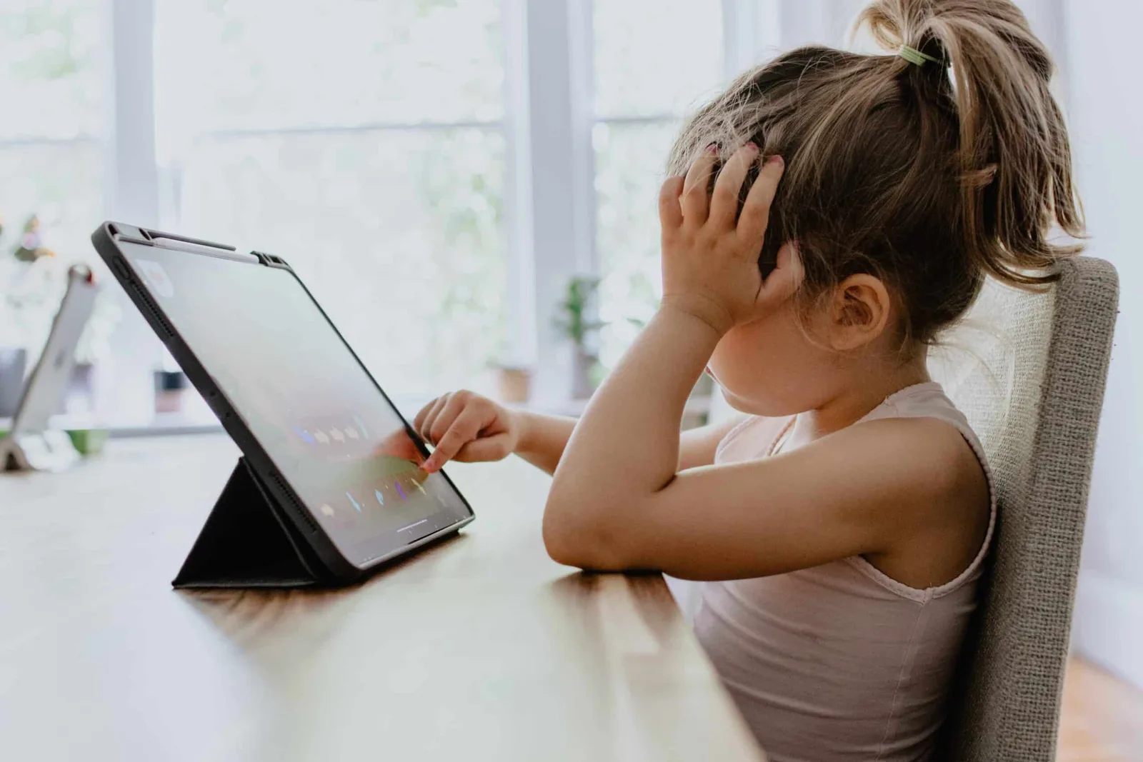 Un copil îngrijorat, concentrat pe un dispozitiv digital, reflectând la experiențele online.