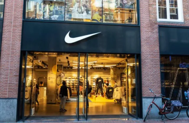 Magazin Nike cu intrare modernă și logo mare pe fațadă.