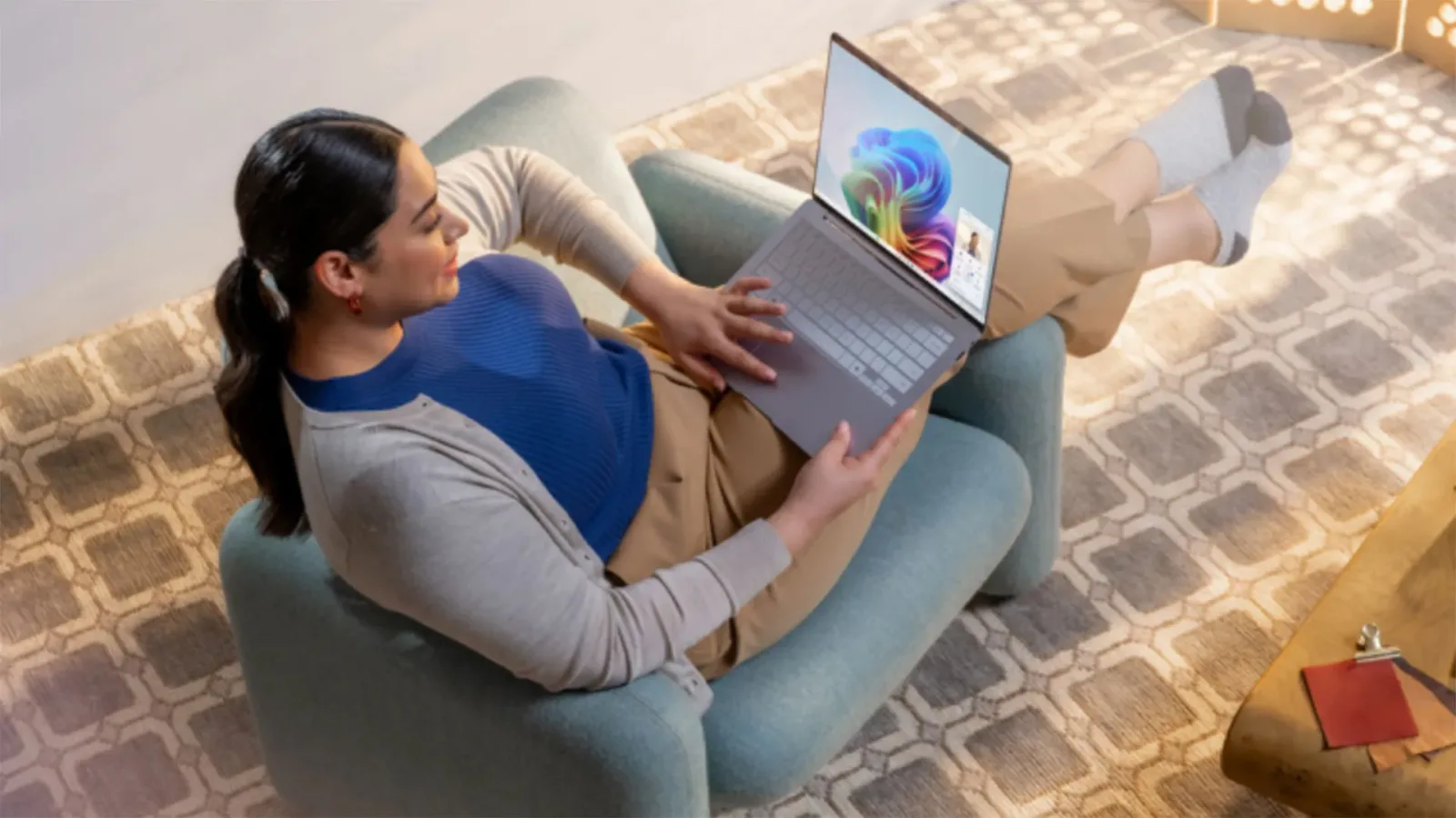 Utilizator configurând Windows 11 pe un laptop, relaxat într-un fotoliu confortabil.