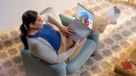 Utilizator configurând Windows 11 pe un laptop, relaxat într-un fotoliu confortabil.