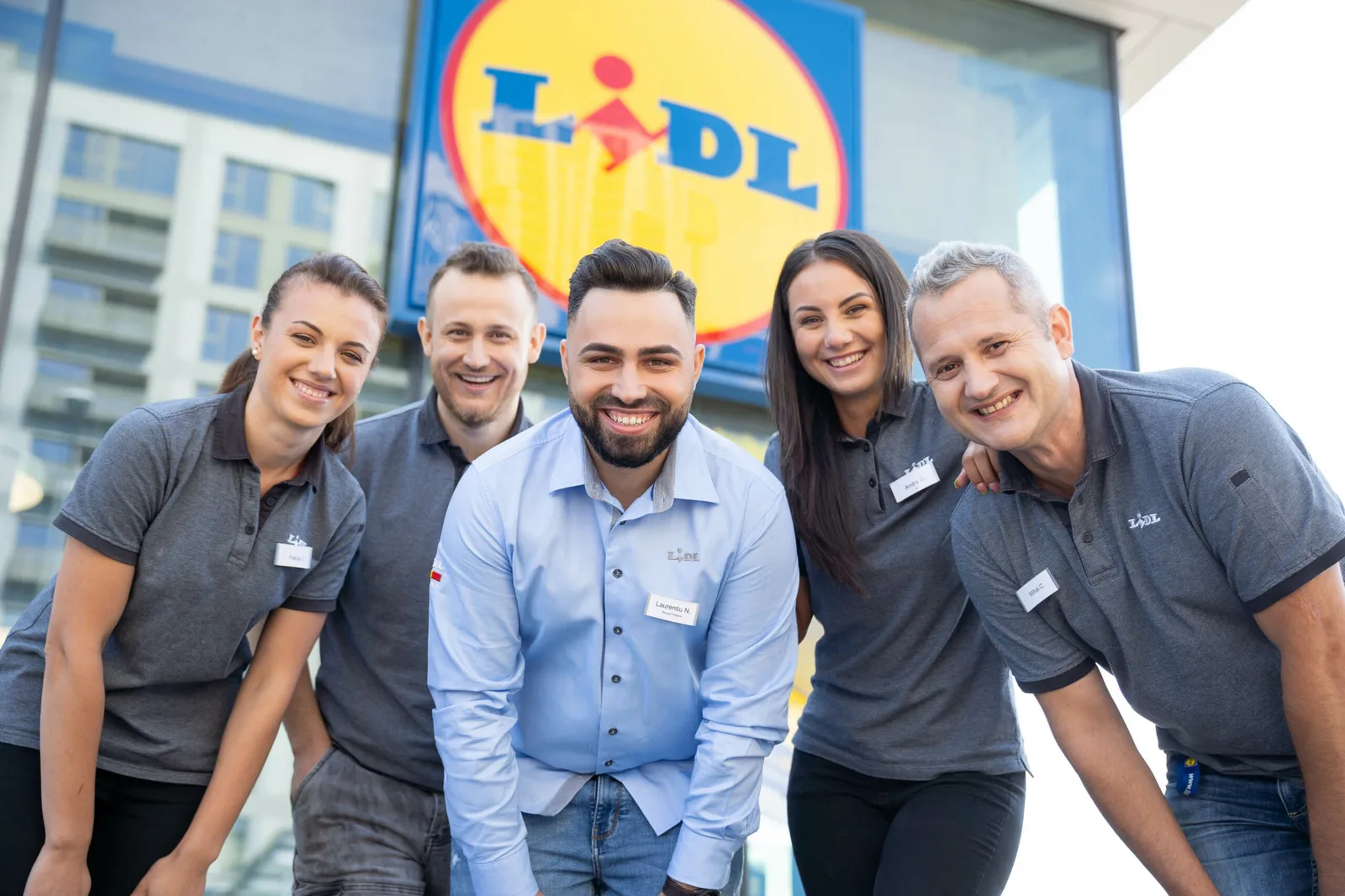 Echipa Lidl zâmbind în fața unui nou magazin deschis.