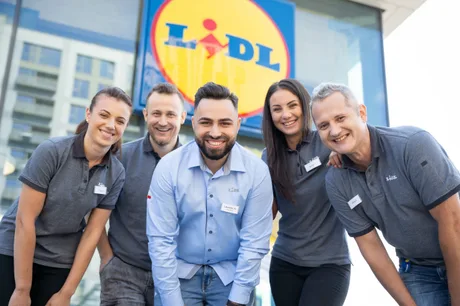 Echipa Lidl zâmbind în fața unui nou magazin deschis.