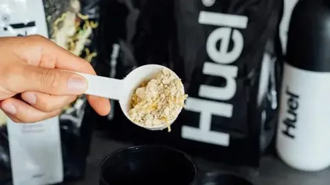 Pulbere Huel pentru shake-uri nutritive, preparată cu măsură.