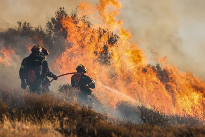 Pompieri intervenind pentru stingerea unui incendiu de vegetație în Grecia.